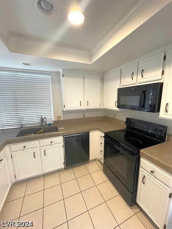 kitchen featuring a tray ceiling, black appliances, light tile patterned floors, and white cabinets