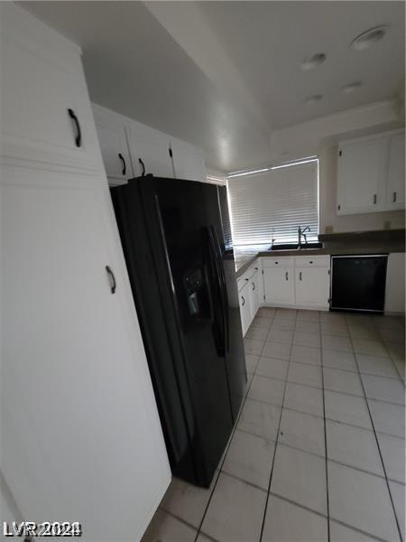 kitchen with light tile patterned flooring, white cabinetry, black appliances, and sink