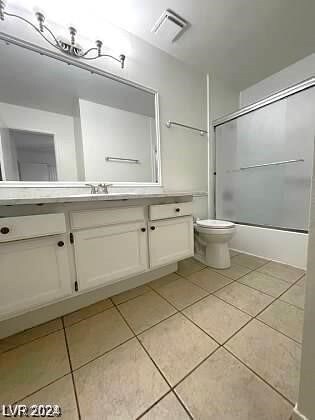 full bathroom featuring combined bath / shower with glass door, vanity, tile patterned flooring, and toilet