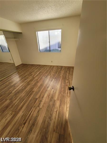 empty room with a textured ceiling and hardwood / wood-style floors