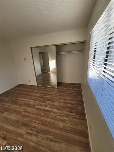 unfurnished bedroom with dark hardwood / wood-style floors, a closet, and a textured ceiling