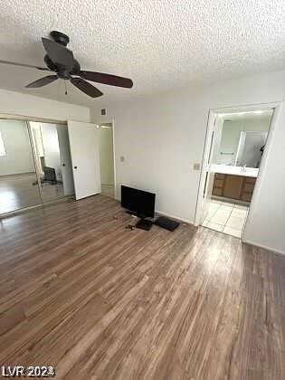 unfurnished living room with a textured ceiling, wood-type flooring, and ceiling fan