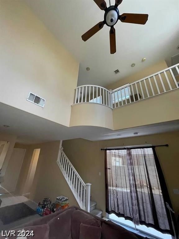 stairway with ceiling fan and a high ceiling