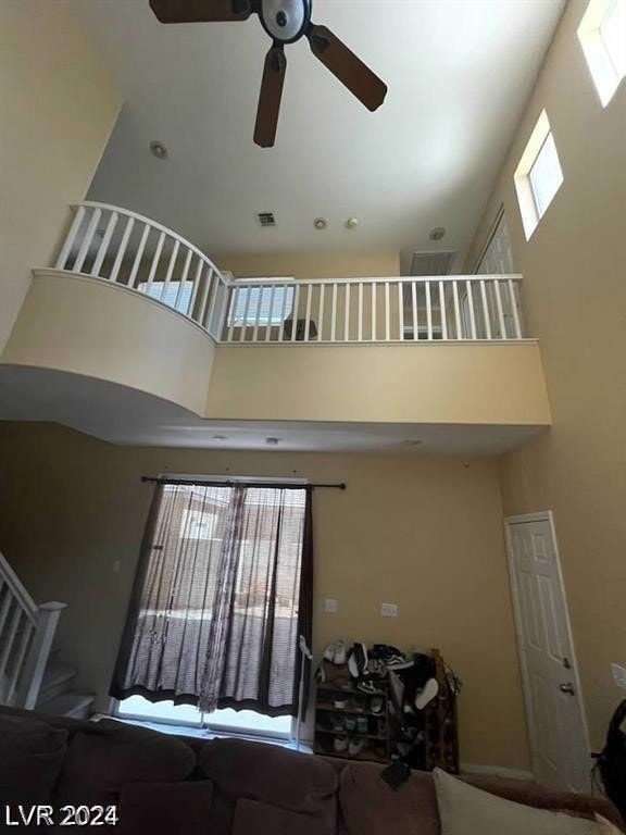 living room with ceiling fan, a towering ceiling, and plenty of natural light