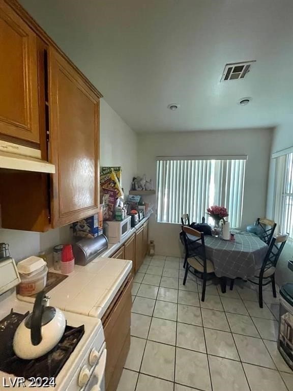 kitchen featuring plenty of natural light, tile counters, white appliances, and light tile patterned floors