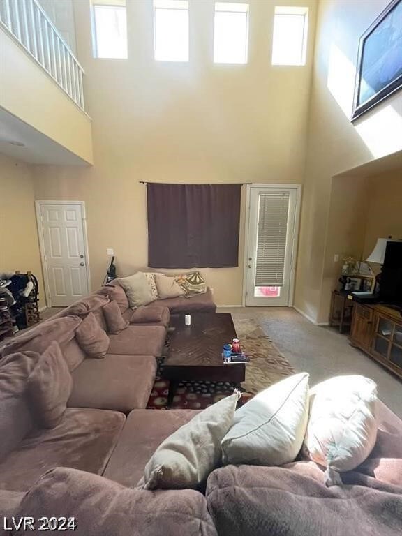 carpeted living room with a towering ceiling