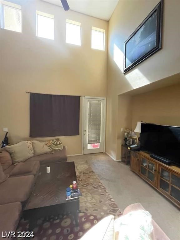 carpeted living room featuring a towering ceiling