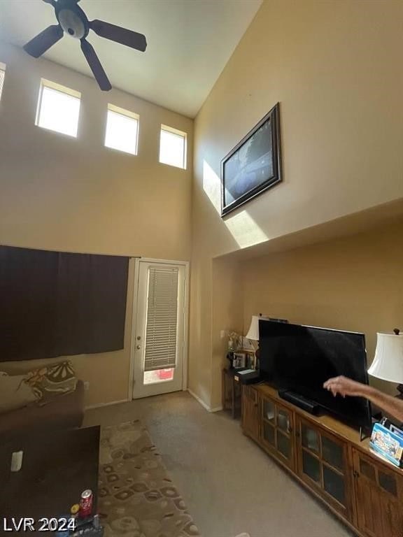 carpeted living room featuring a high ceiling, a wealth of natural light, and ceiling fan