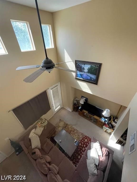 unfurnished living room with a high ceiling, carpet, and ceiling fan