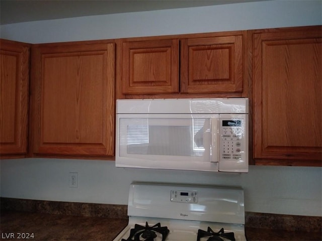 1501 Linnbaker Ln Unit 103, Las Vegas, NV 89110 - kitchen view of white microwave, gas range oven, brown cabinets, and dark countertops