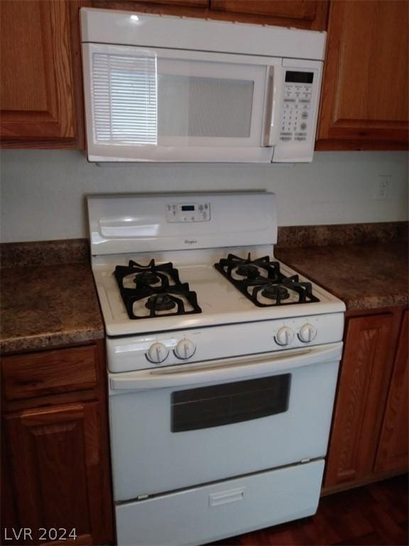 1501 Linnbaker Ln Unit 103, Las Vegas, NV 89110 - kitchen with white appliances, brown cabinetry, and dark countertops