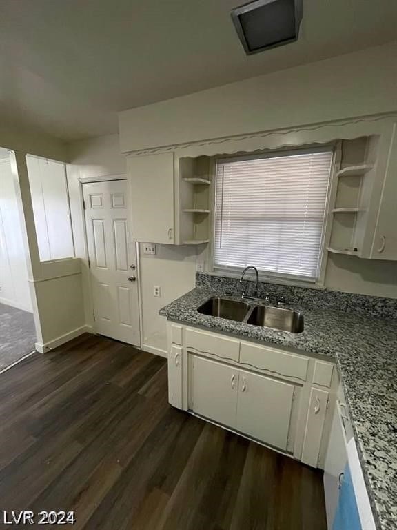 kitchen with sink, white cabinetry, light stone counters, and dark hardwood / wood-style floors