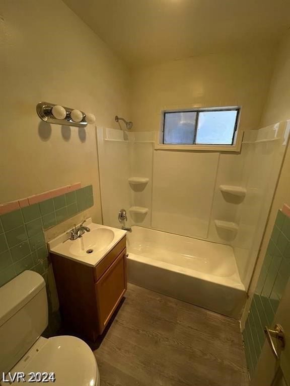 full bathroom with hardwood / wood-style floors, tile walls, toilet, bathing tub / shower combination, and vanity