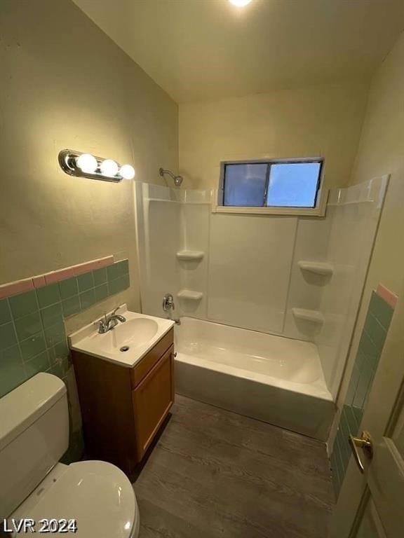 full bathroom featuring vanity, wood-type flooring, tile walls, tub / shower combination, and toilet