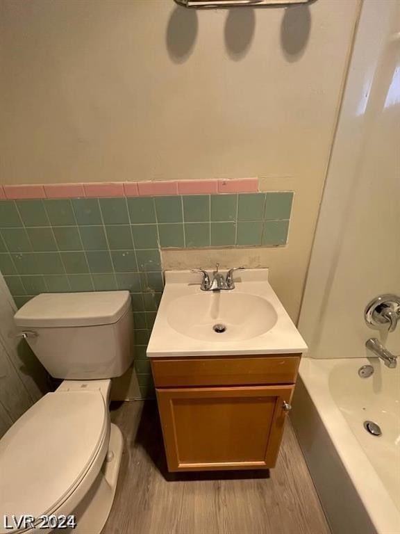 full bathroom with wood-type flooring, toilet, and vanity