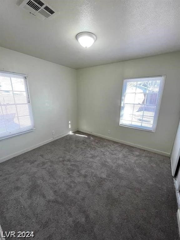 carpeted empty room featuring a textured ceiling