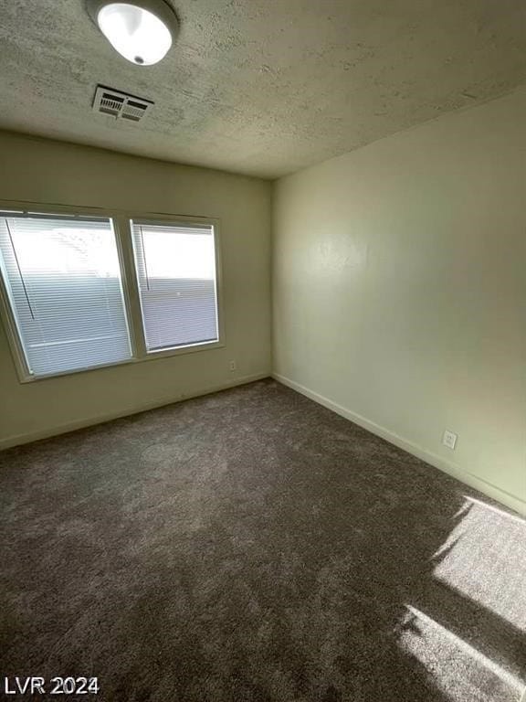 unfurnished room featuring carpet flooring and a textured ceiling