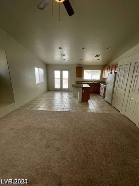 kitchen with a kitchen island, sink, white fridge, light colored carpet, and ceiling fan