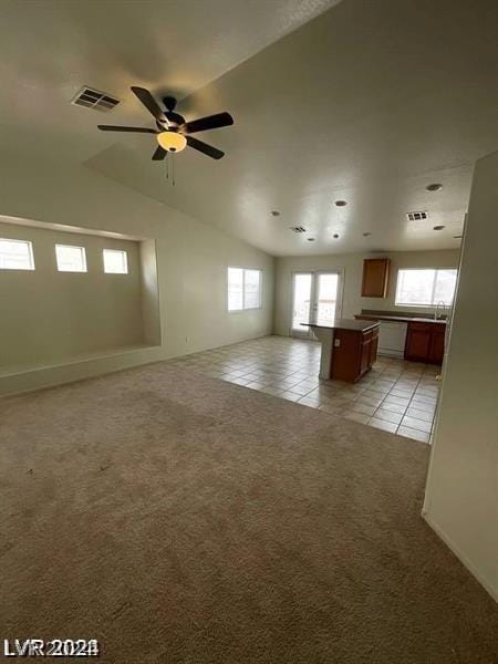 unfurnished living room with ceiling fan, light colored carpet, and vaulted ceiling