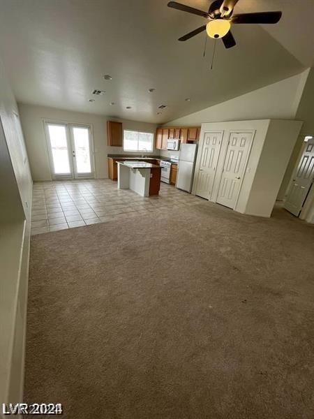 unfurnished living room featuring light carpet, lofted ceiling, and ceiling fan