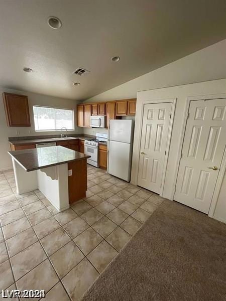 kitchen featuring sink, a breakfast bar area, a center island, vaulted ceiling, and white appliances