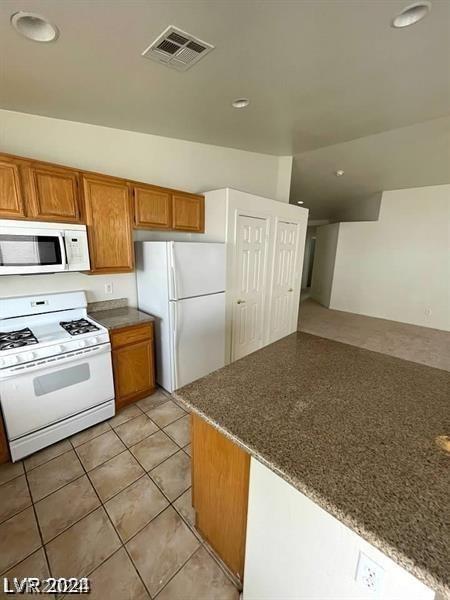 kitchen featuring light tile patterned flooring, white appliances, and kitchen peninsula