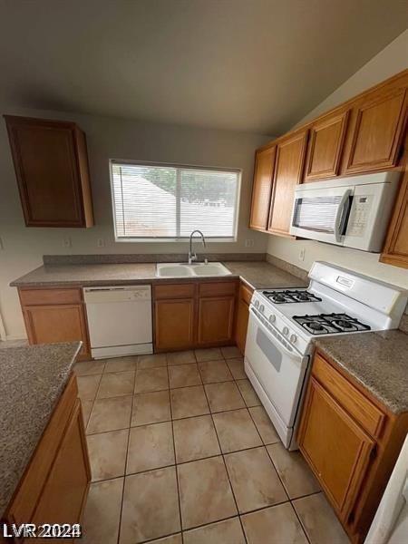 kitchen featuring sink, white appliances, vaulted ceiling, and light tile patterned floors