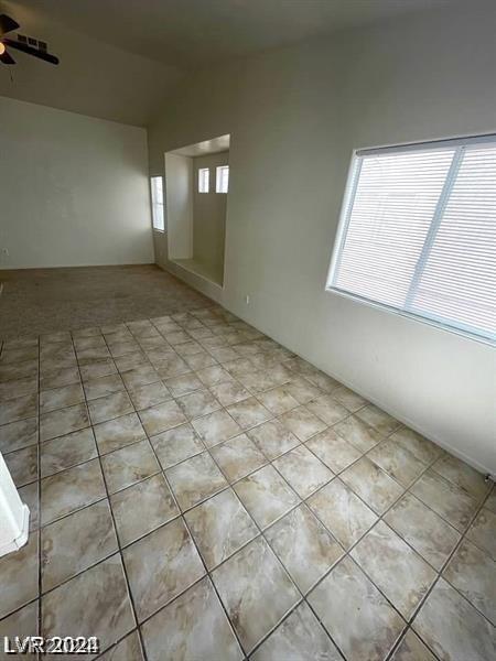 tiled spare room with lofted ceiling, ceiling fan, and a healthy amount of sunlight