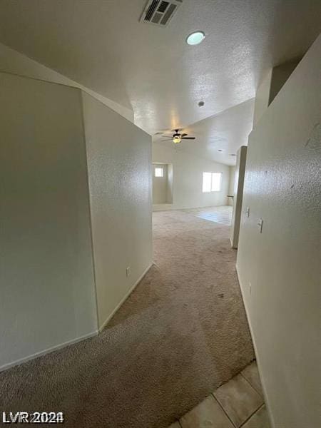 corridor with light carpet and a textured ceiling