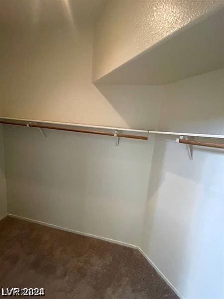 walk in closet featuring dark colored carpet