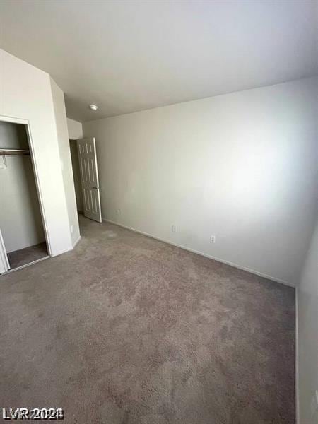 unfurnished bedroom featuring dark carpet and a closet