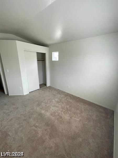 unfurnished bedroom featuring dark carpet and a closet