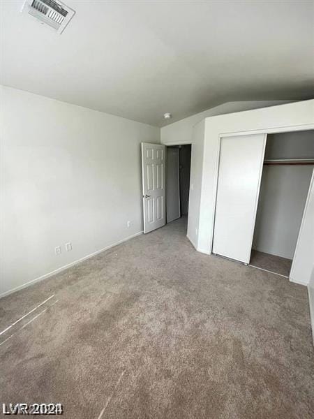 unfurnished bedroom featuring a closet, lofted ceiling, and carpet