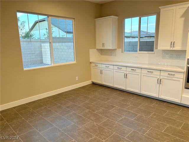 kitchen with decorative backsplash, stainless steel oven, and white cabinets