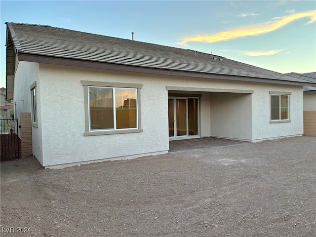 back house at dusk featuring a patio