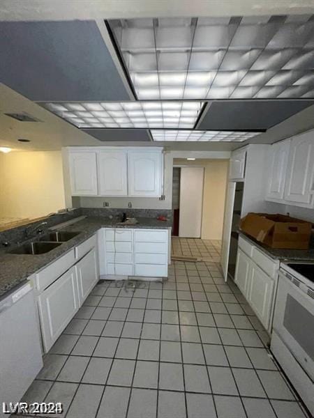 kitchen featuring light tile patterned flooring, white cabinetry, sink, dark stone counters, and white appliances