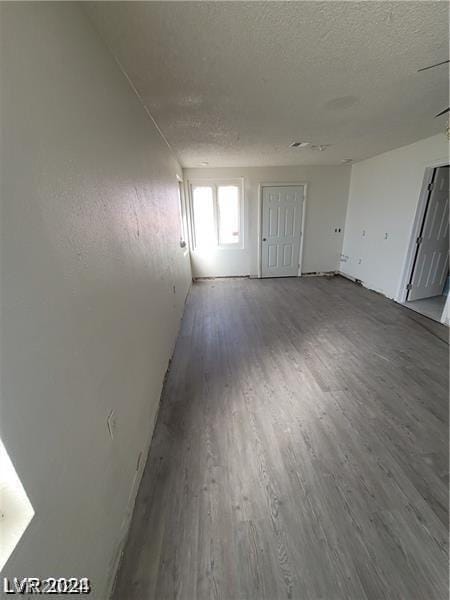 unfurnished room with a textured ceiling and dark hardwood / wood-style flooring