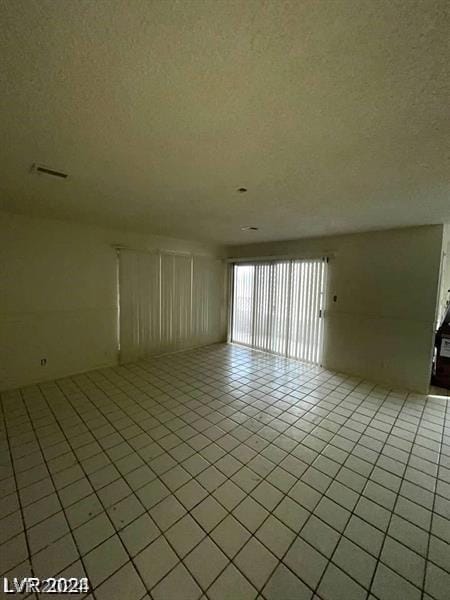 spare room with a textured ceiling and light tile patterned floors