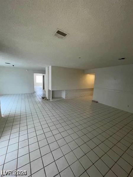 spare room with light tile patterned flooring and a textured ceiling