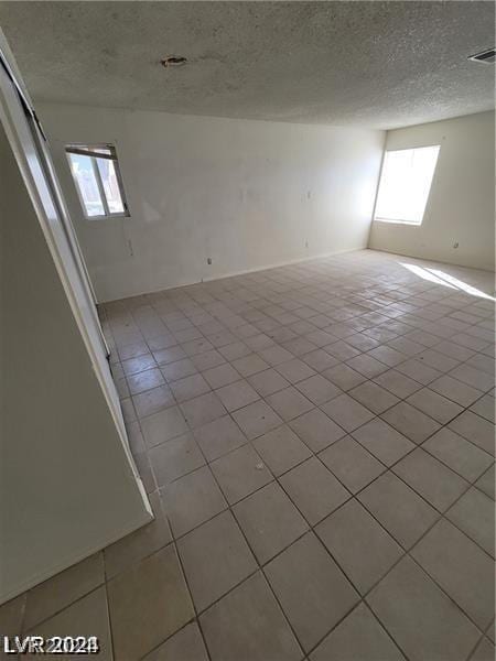 tiled spare room with a wealth of natural light and a textured ceiling