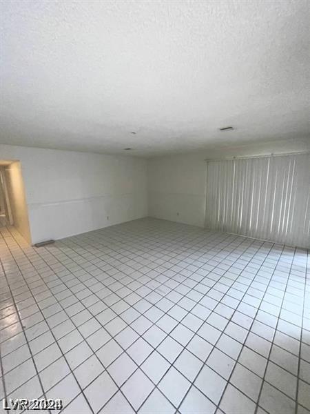 tiled spare room featuring a textured ceiling