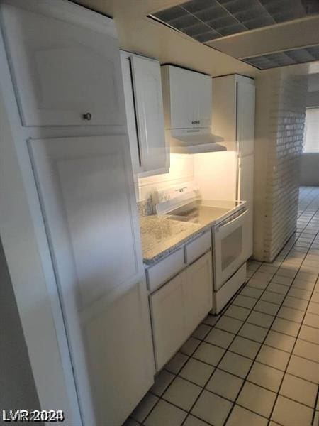 kitchen featuring white cabinetry, white electric range oven, light tile patterned flooring, and tasteful backsplash