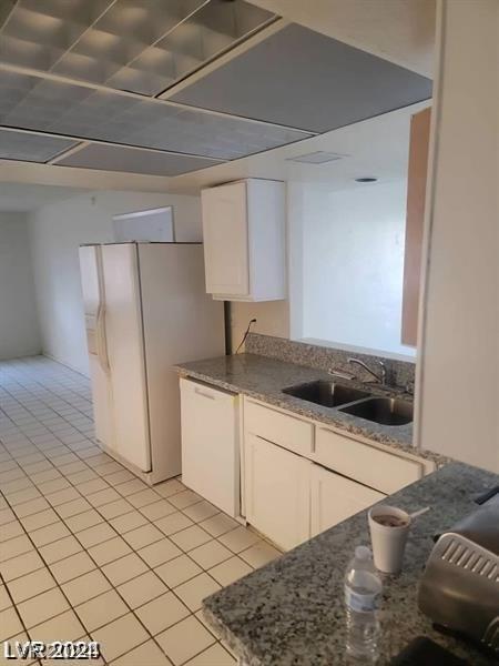 kitchen with white appliances, light tile patterned floors, sink, and white cabinets