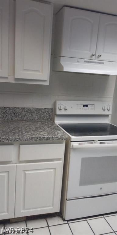 kitchen with white electric stove, exhaust hood, white cabinets, and light tile patterned flooring