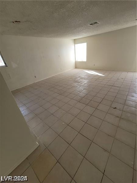 tiled spare room featuring a textured ceiling