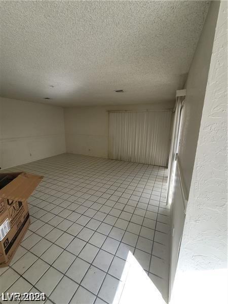 empty room featuring a textured ceiling and light tile patterned floors