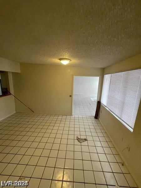 tiled spare room featuring a textured ceiling