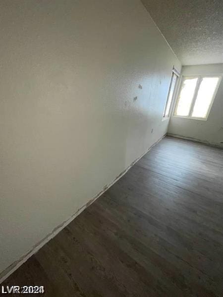 additional living space with dark hardwood / wood-style flooring and a textured ceiling