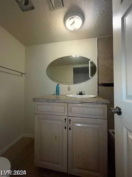 bathroom with vanity, toilet, and a textured ceiling