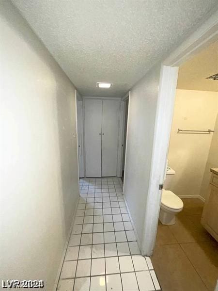 hall featuring light tile patterned flooring and a textured ceiling